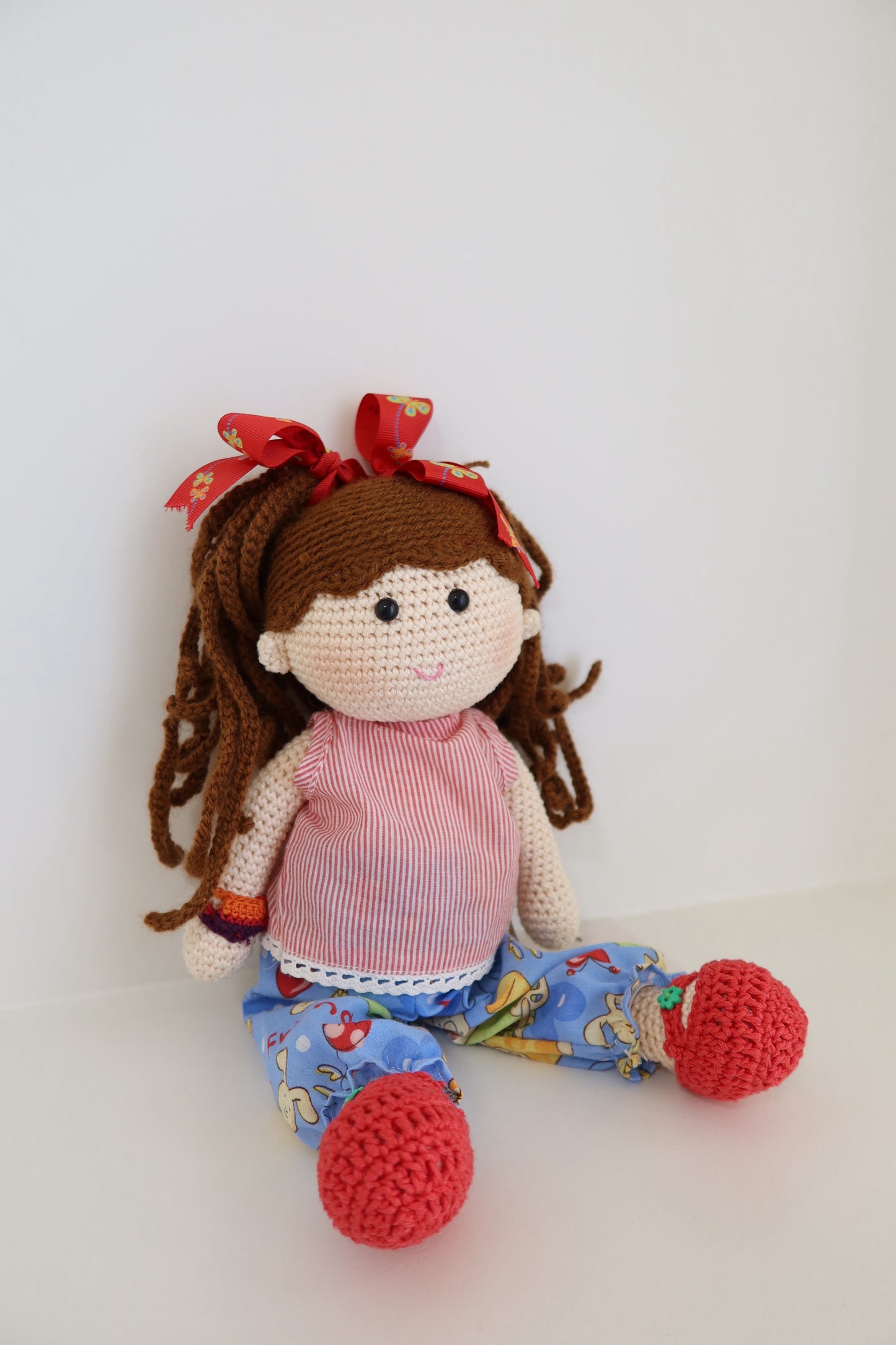 Muñequita tejida - pelo cafe con moños rojo